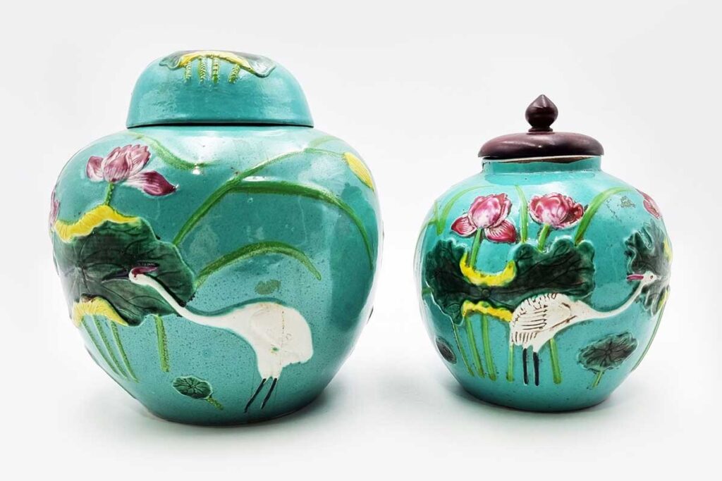 CHINESE PORCELAIN GINGER JARS pair in style of Wang Bing Rong, featuring a bright, glaze and raised relief lotus decoration, one with wooden lid. Height: 18 cm, 16 cm.