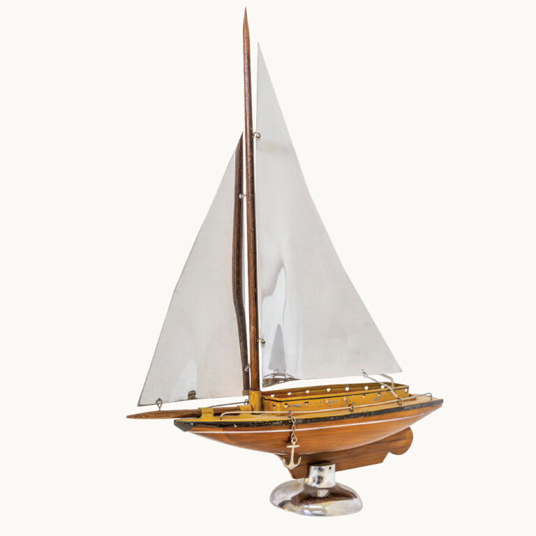 A model yacht vase with a lined wooden hull and chrome sails on a chrome stand