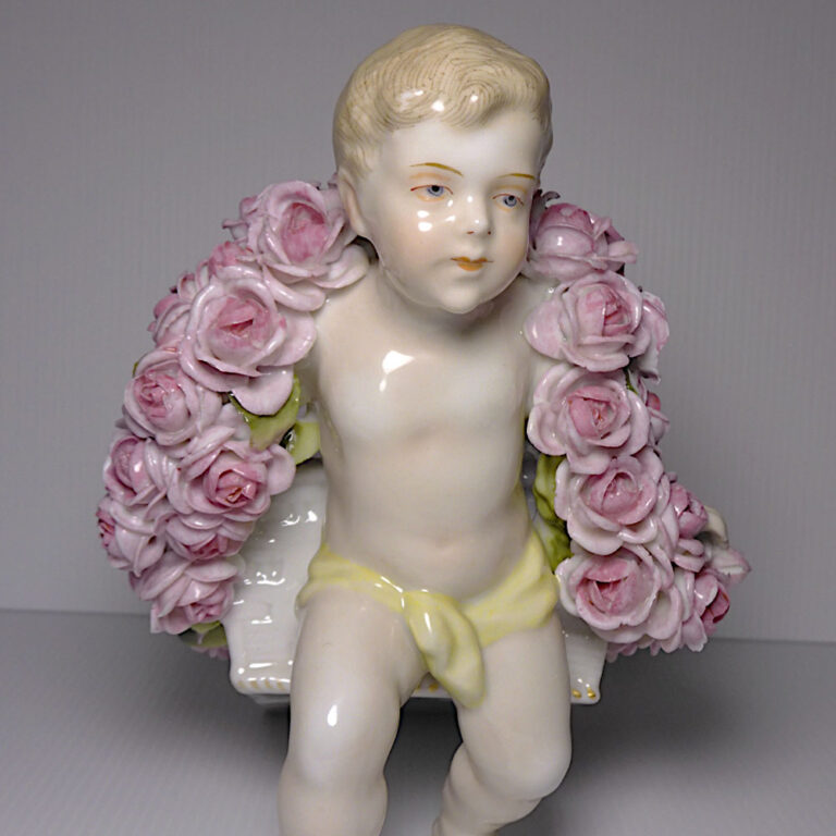 Plaue Schierholz porcelain figurine, a hand painted cherub pulling a floral cart