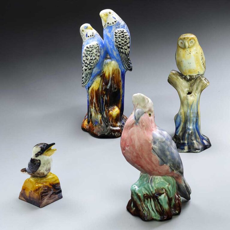 A group of bird figurines by Grace Seccombe - a pair of budgerigars, a Southern Boobook Hawk Owl, a galah and a kookaburra, each set on a naturalistic base. at Graham Lancaster Auction.