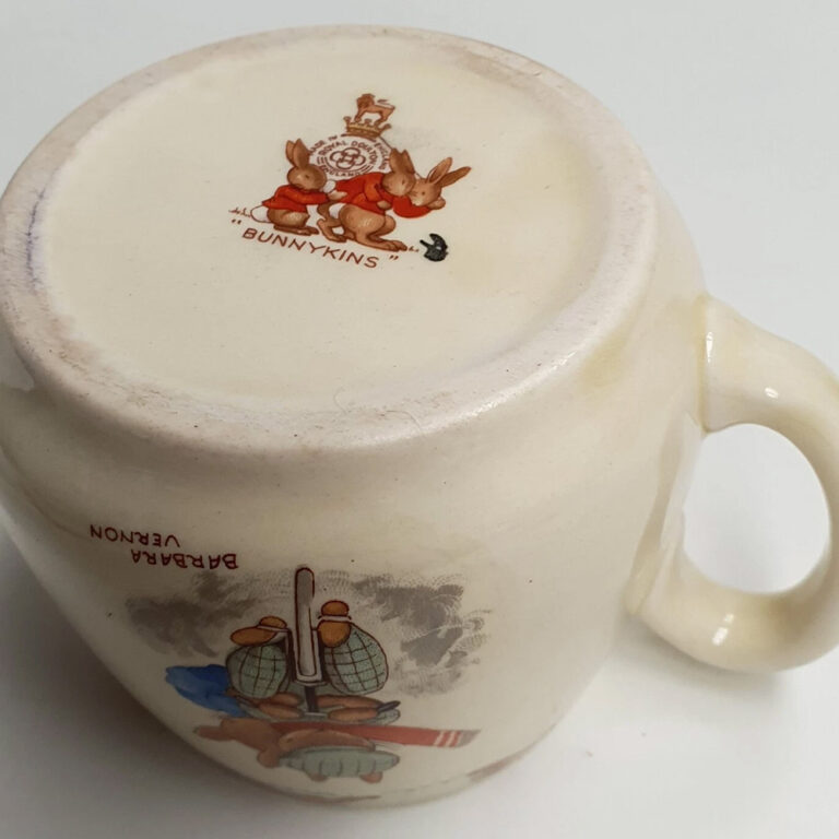 A Royal Doulton Bunnykins mug designed by Barbara Vernon, Gardening /Cycling. Don shape c.1937-53.