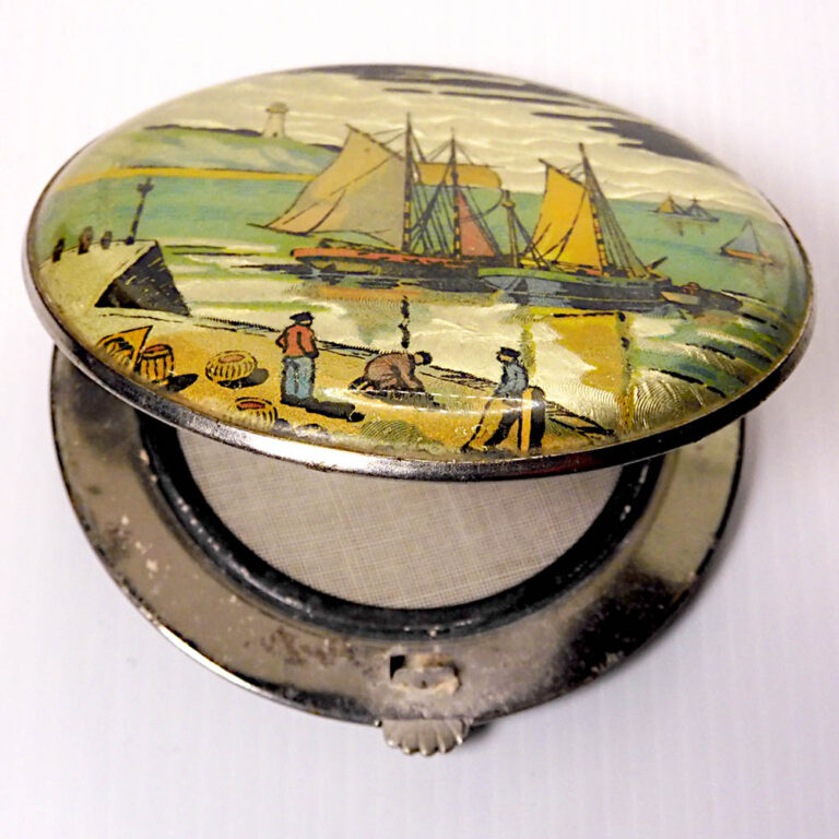 A vintage compact with a tin foiled back and a charming seaside print.