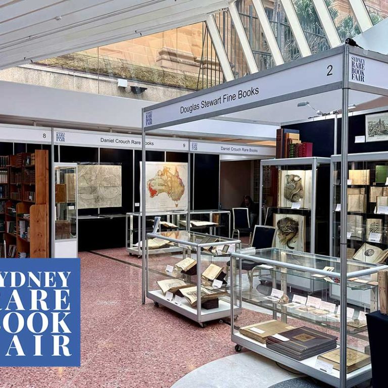 Exhibitor stands and glass display cases beneath the skylit Glasshouse atrium at the Sydney Rare Book Fair, State Library of NSW.